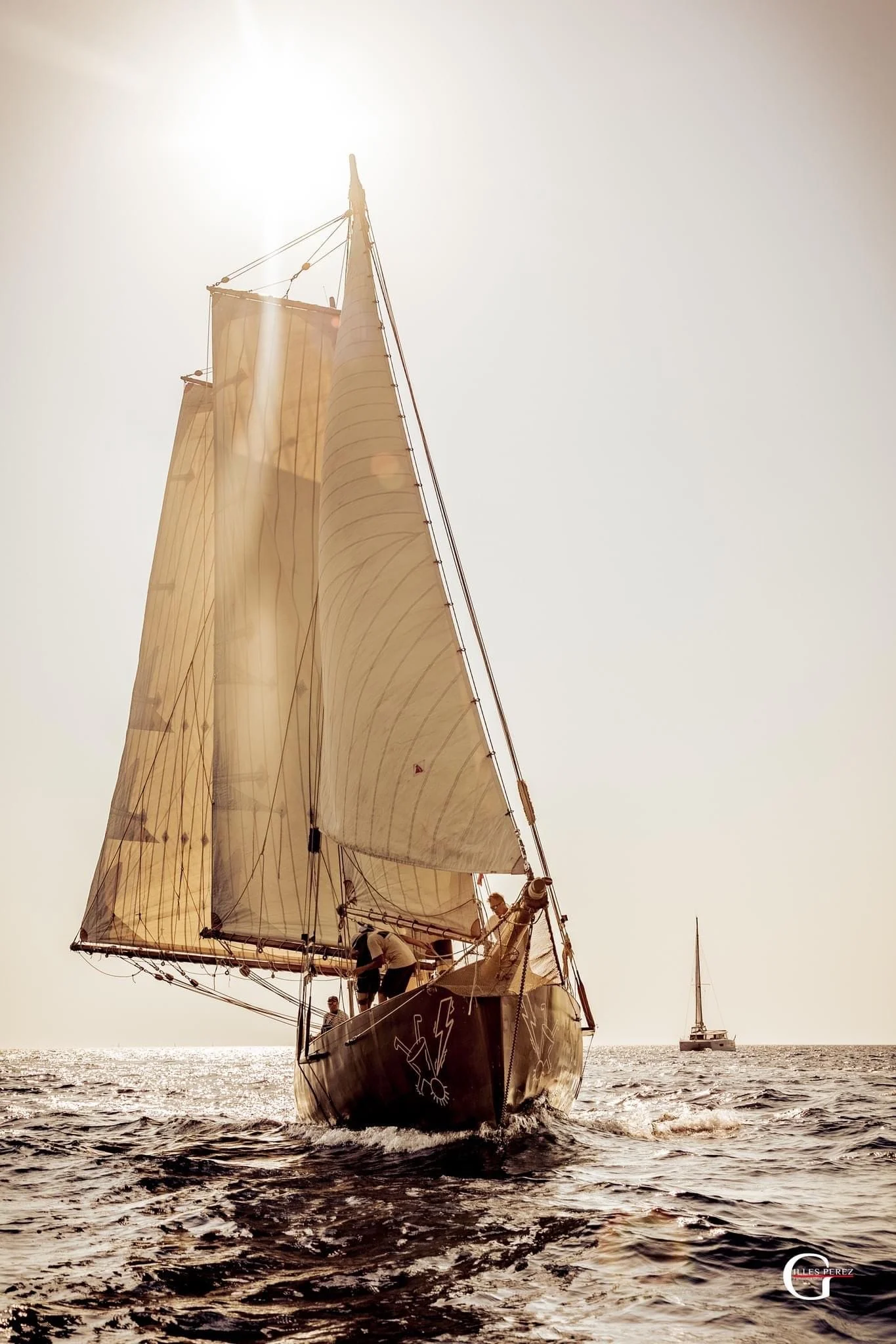 Grande Zot de face, voiles auriques déployées dans une lumière chaude ; crédit photographique visible en bas à droite